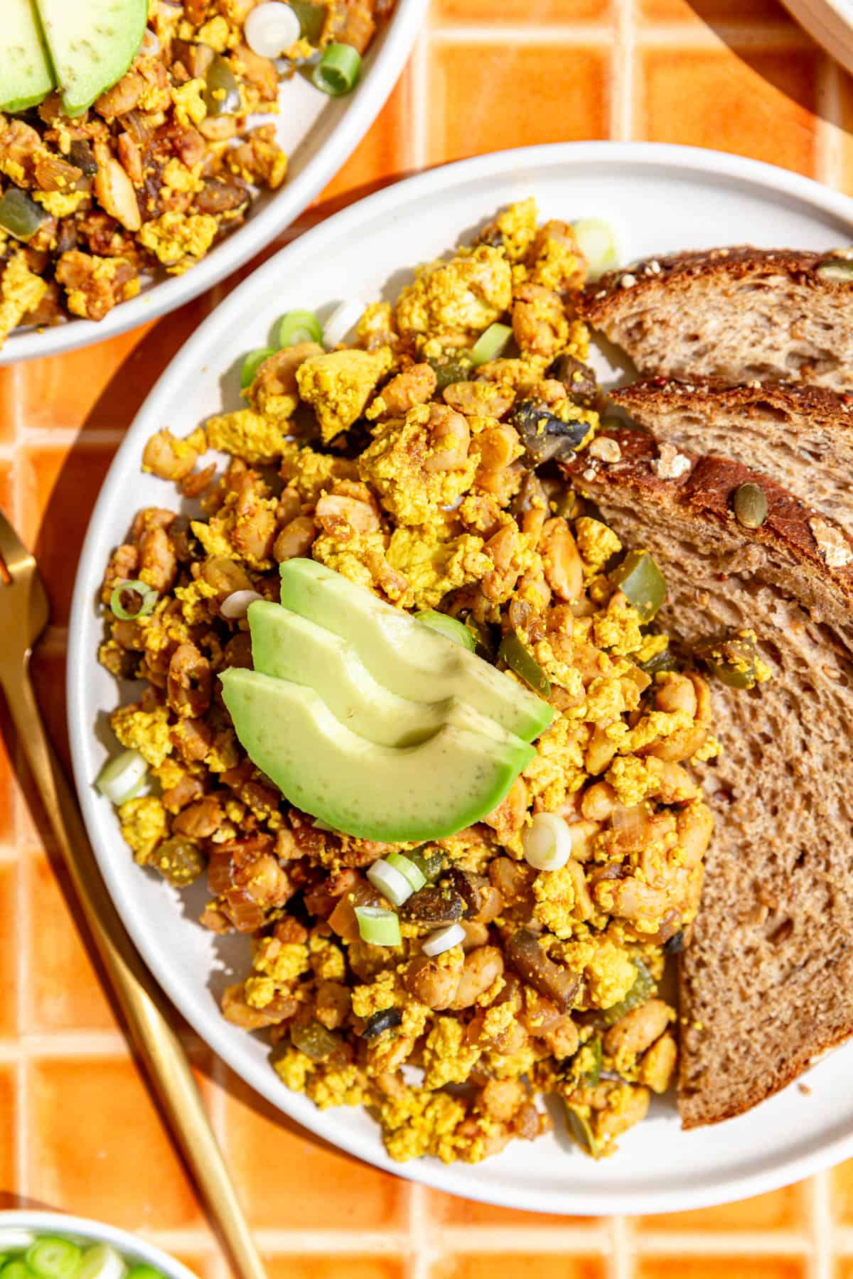 A plate of tempeh scramble, and a fork, ready to serve.