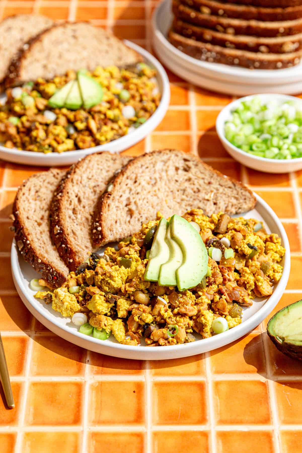 Several plates of tempeh scramble and a stack of toast.