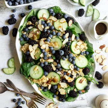 A large platter of spinach blueberry salad.