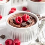 Vegan Tofu Chocolate Mousse in a ramekin, topped with raspberries and chocolate.