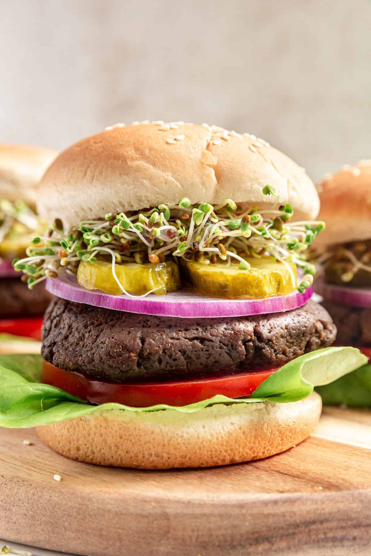 A seitan burger on a cutting board, loaded with toppings and served on a bun.