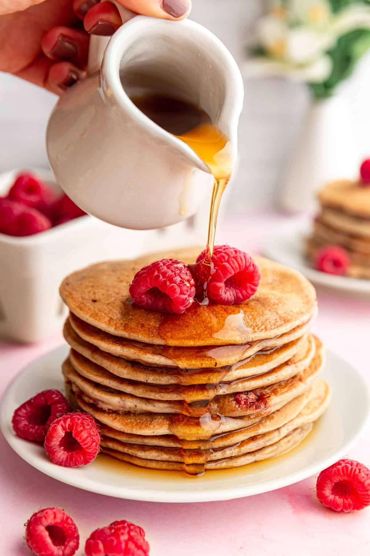 Pouring maple syrup onto Vegan Raspberry Lemon Pancakes