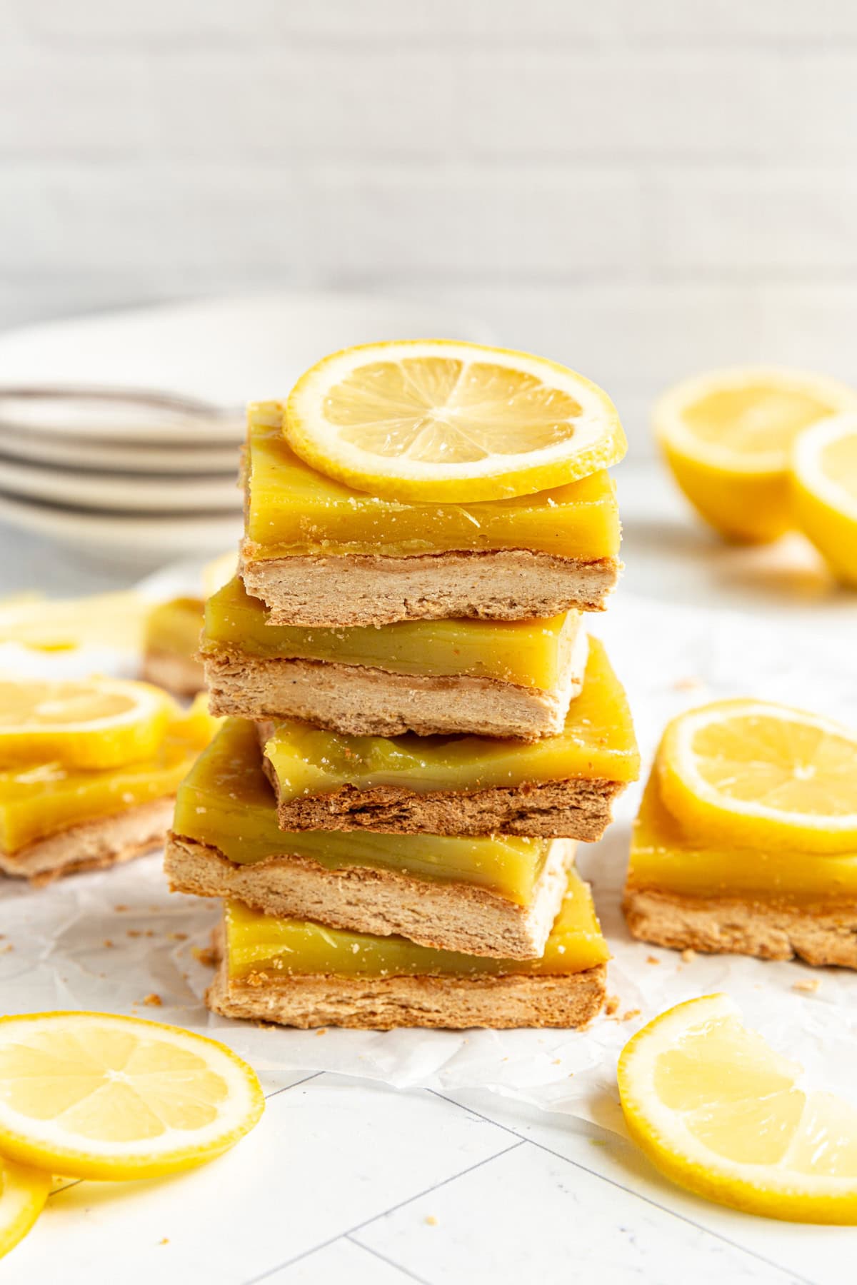 Plant-Based Lemon Bars stacked and surrounded by lemons.