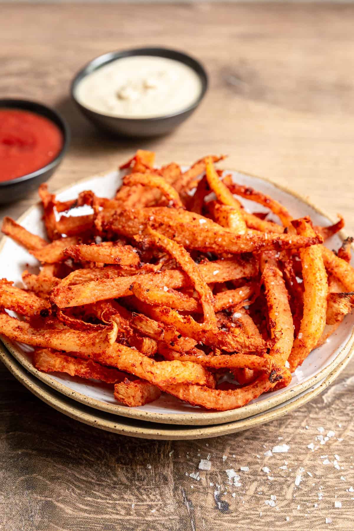 A bowl of Jicama air fryer fries with two bowls of ketchup and mayo.