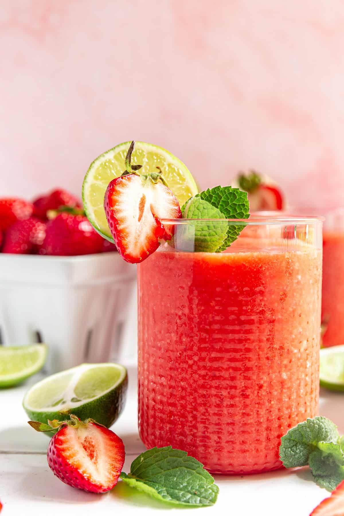 A glass of Strawberry Daiquiri Mocktail and a basket of strawberries.