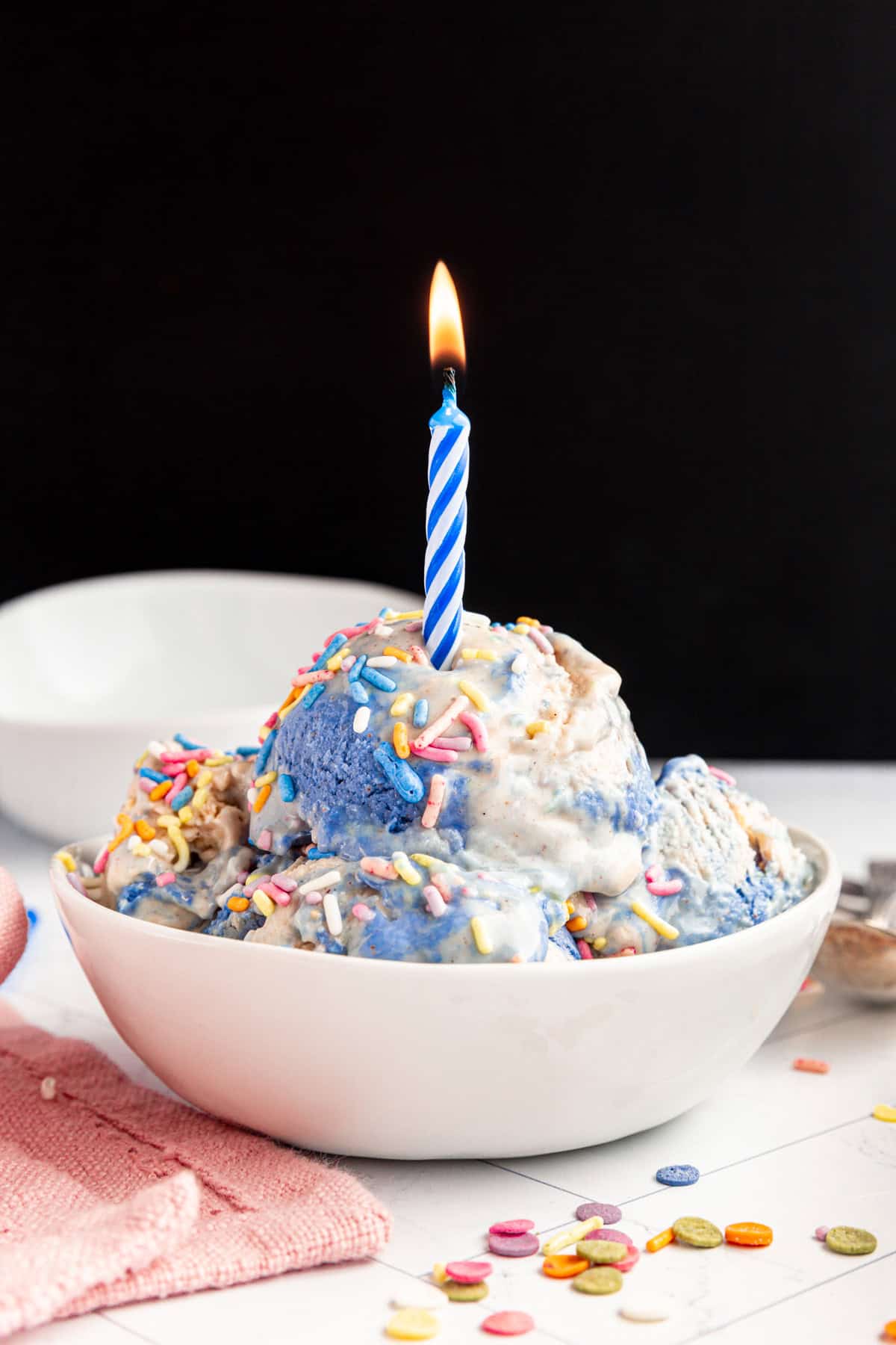 A lit birthday candle in a bowl of Vegan Birthday Cake Batter Ice Cream.
