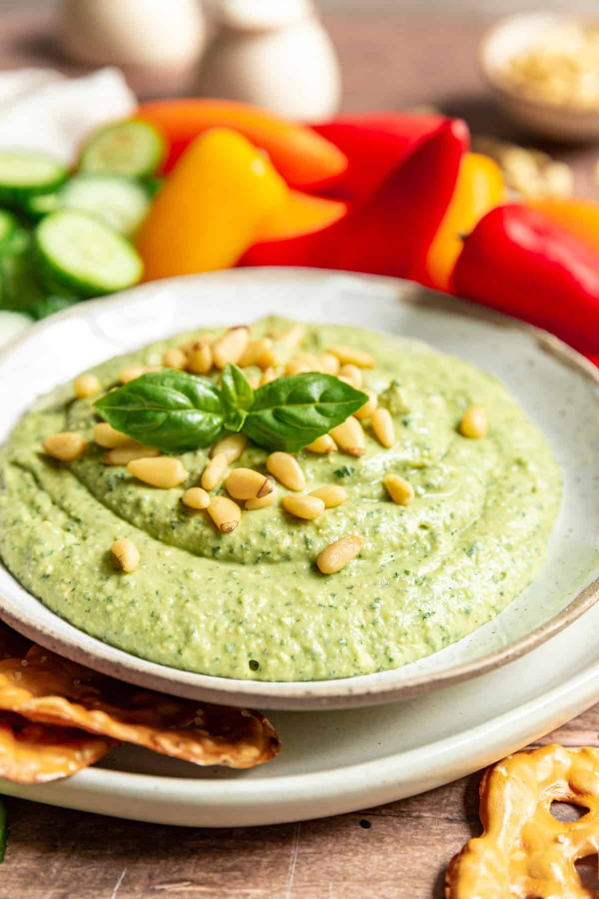 A bowl of Vegan White Bean Pesto Dip topped with pine nuts.