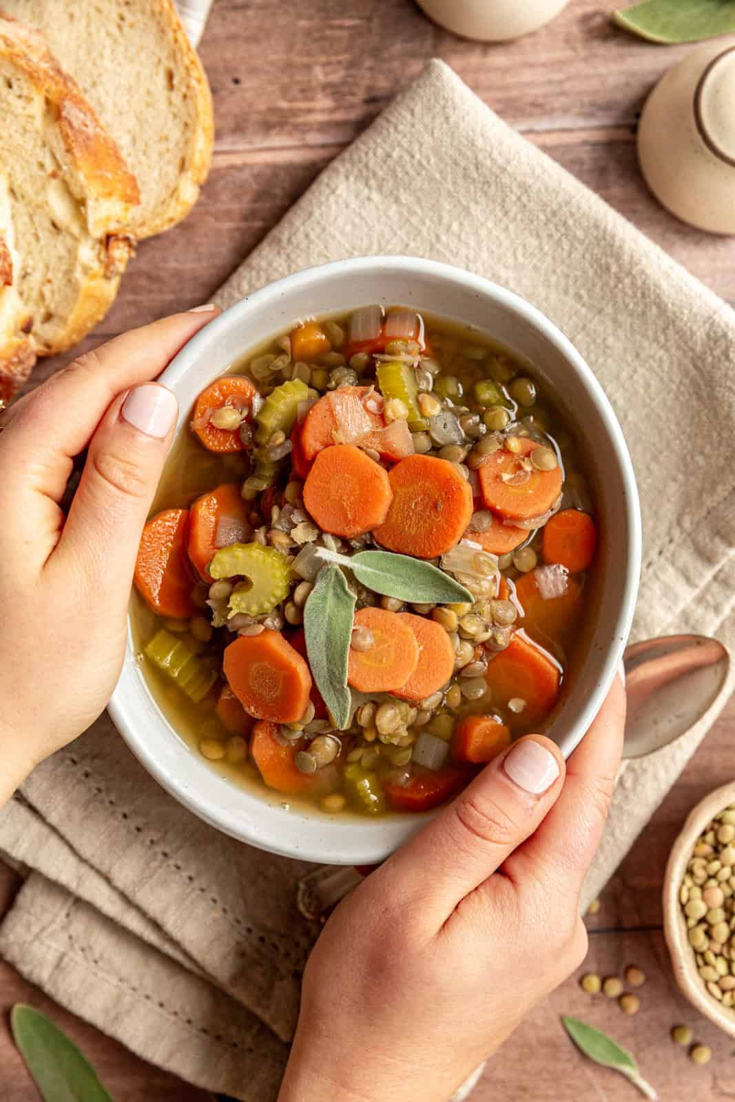 Hands around a bowl of Carrot and Lentil Soup.