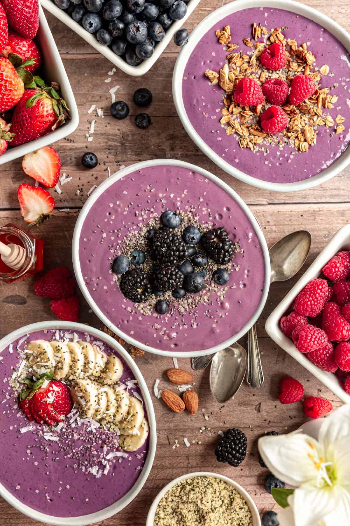 Three High Protein Acai Smoothie Bowls with fresh fruit and seeds.