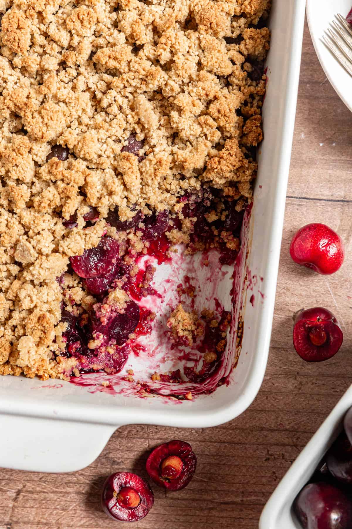 A baking dish with a scoop of Vegan Cherry Crumble removed.