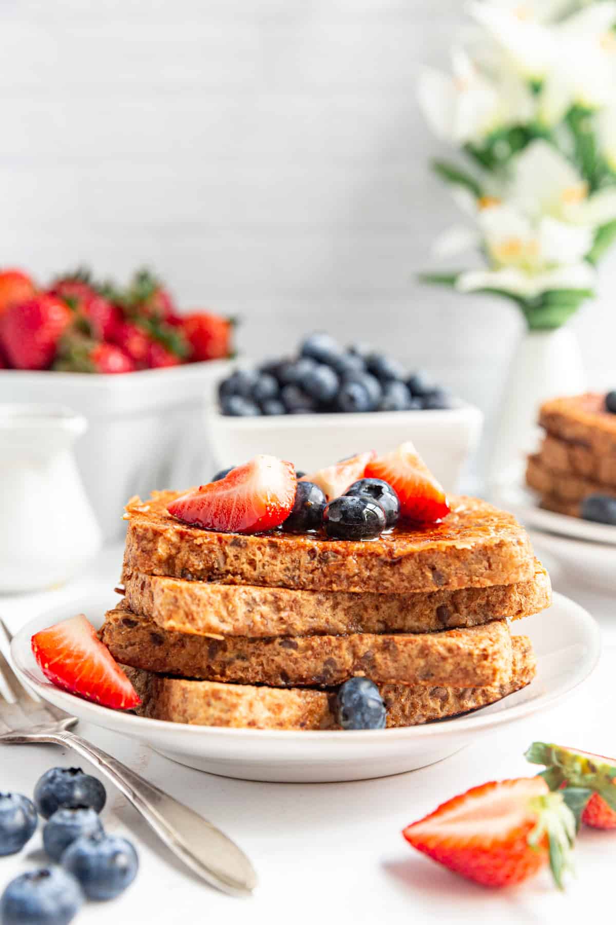 A stack of Vegan High Protein French Toast topped with strawberries and blueberries.