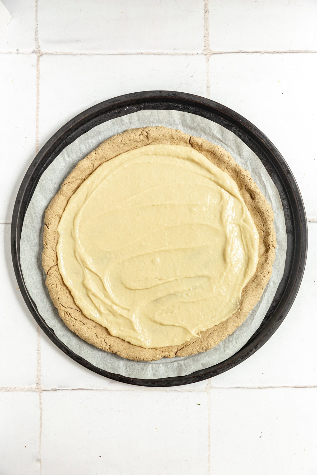 Vegan Tofu Mozzarella spread on oat flour pizza crust, before baking.