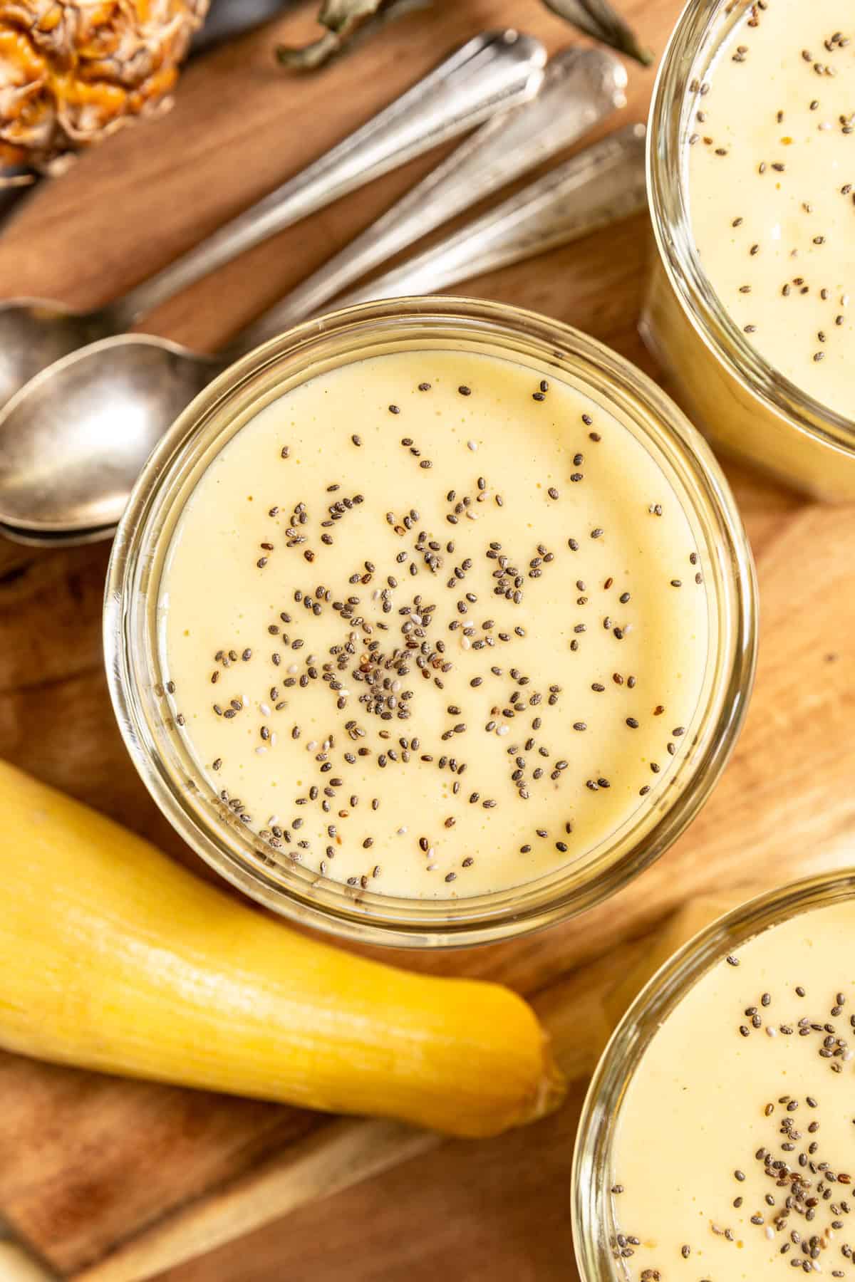 A glass of yellow squash smoothie with a summer squash.