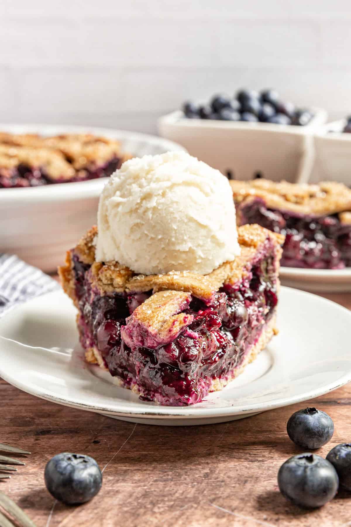 A slice of Gluten Free Vegan Blueberry Pie with a scoop of ice cream on top.