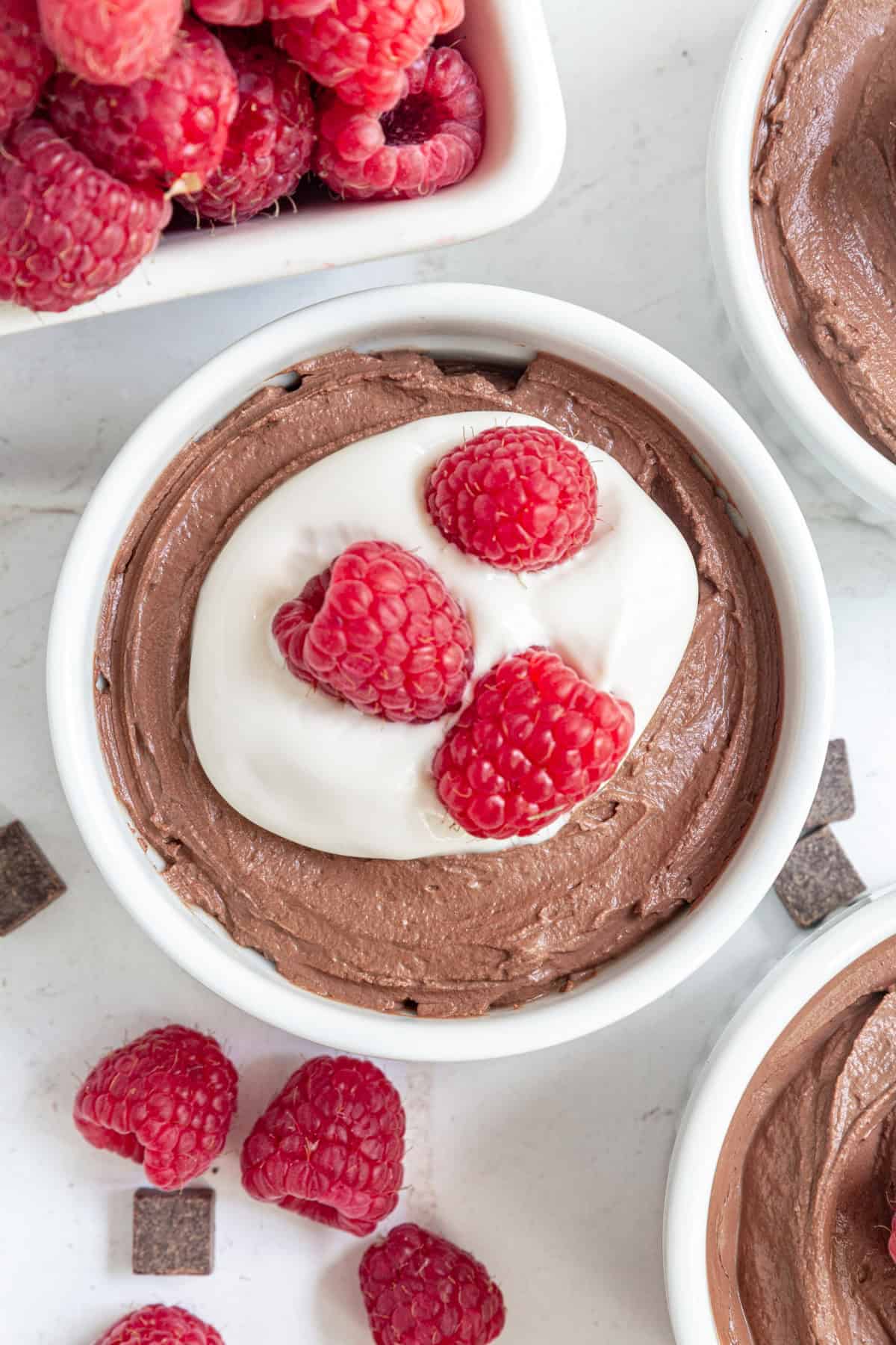 An overhead view of a ramekin of Vegan Tofu Chocolate Mousse topped with yogurt and raspberries.