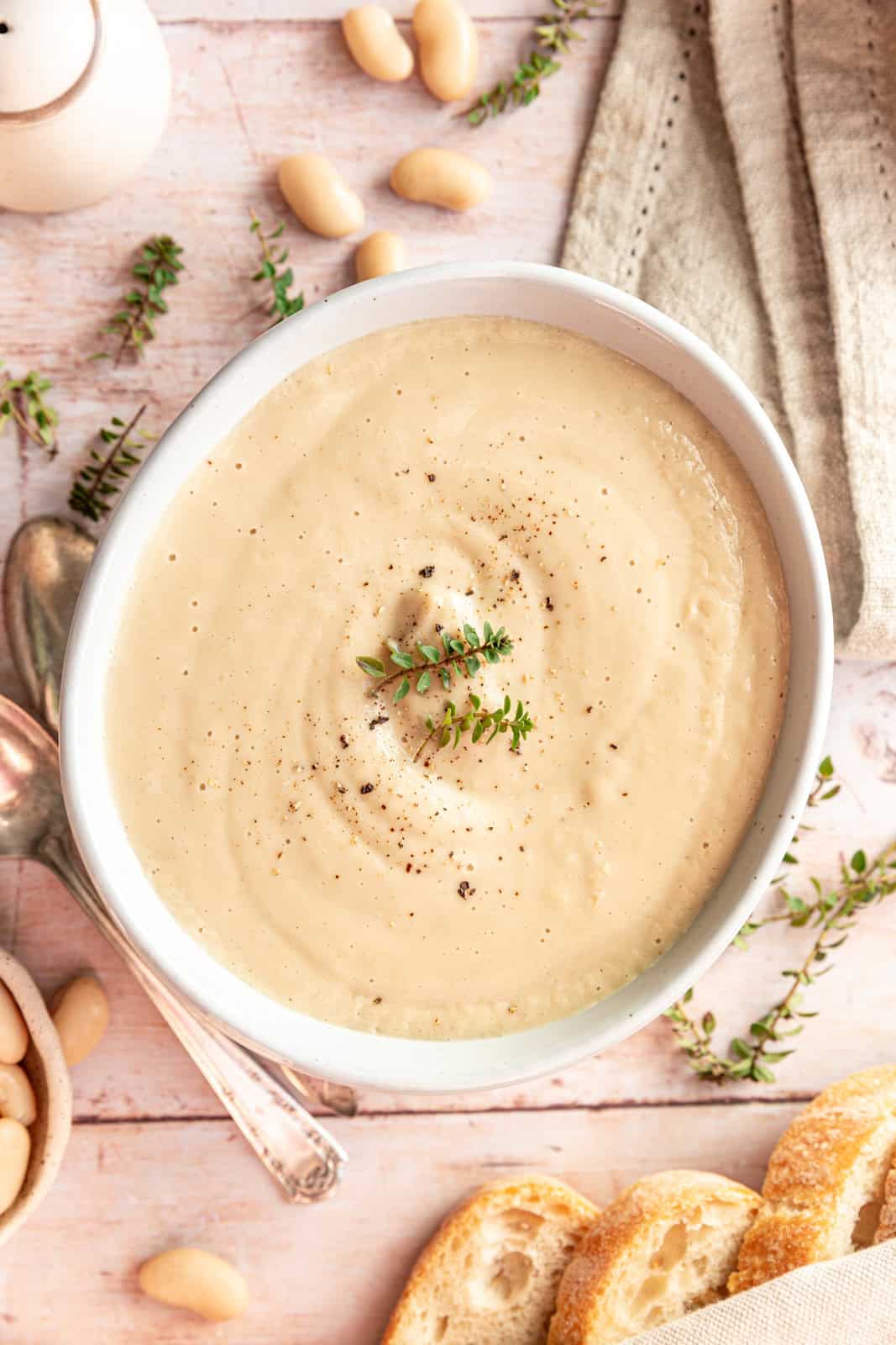 Bowl of Creamy Cauliflower White Bean Soup garnished with thyme.