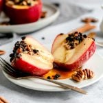 An air fryer baked apple on a plate sliced in half.