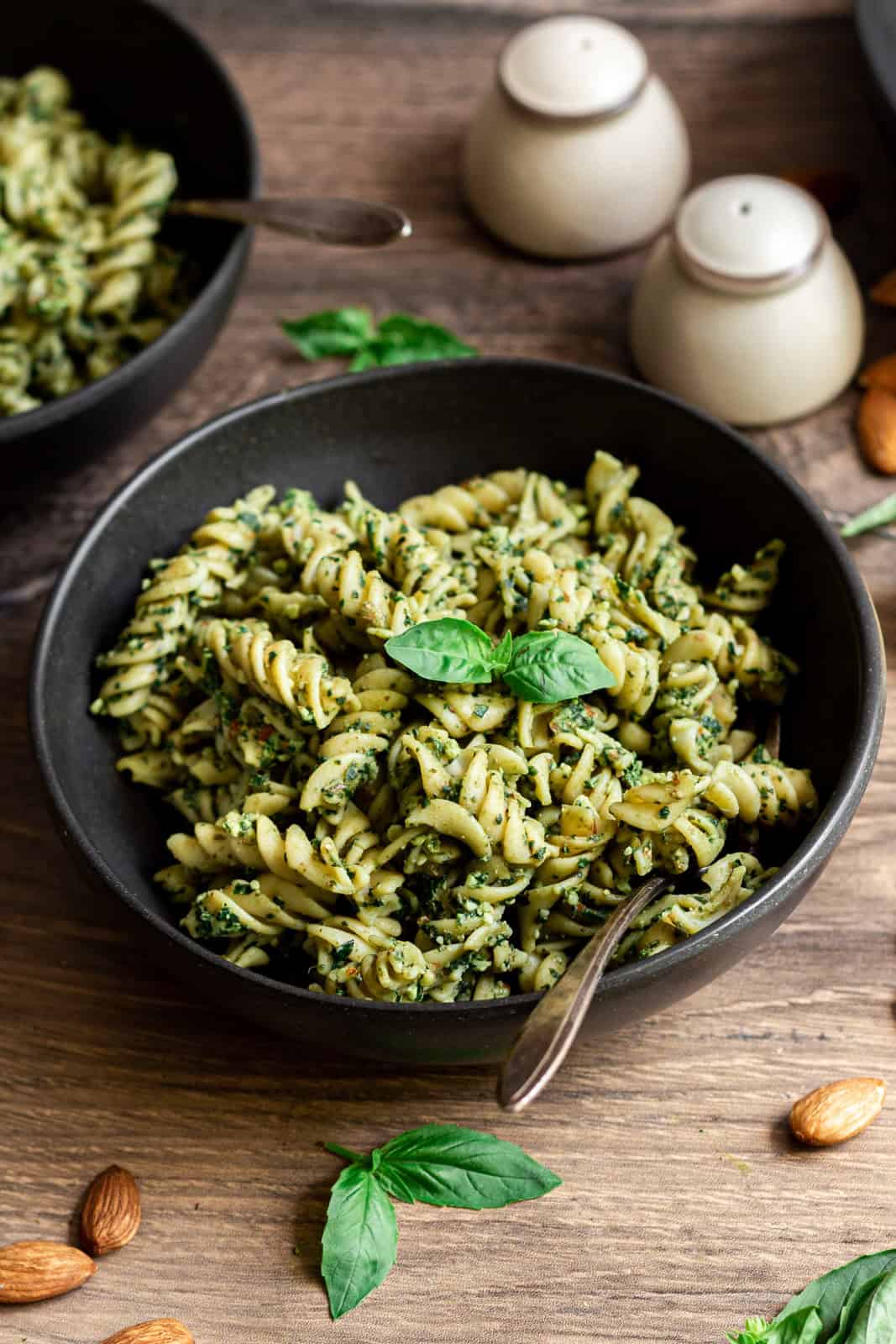 A bowl of vegan almond pesto pasta, garnished with fresh basil.
