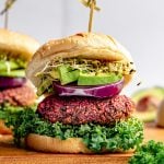 A vegan beet burger loaded with kale, onion, avocado, and sprouts.