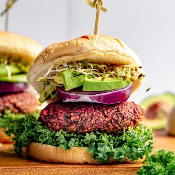 A vegan beet burger loaded with kale, onion, avocado, and sprouts.