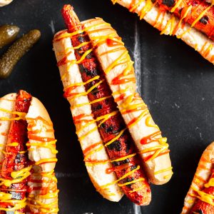 A carrot dog in a bun drizzled with ketchup and mustard.