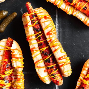A carrot dog in a bun drizzled with ketchup and mustard.