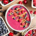 A cherry berry smoothie bowl, topped with berries and nut butter.