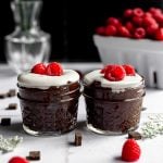 Two jars of cold brew coffee chia pudding topped with vegan yogurt and raspberries.
