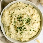 A bowl of garlic bourbon mashed potatoes topped with chives.