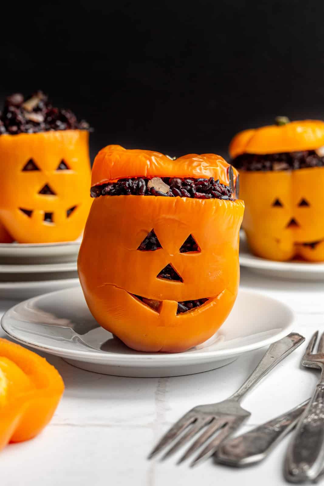 Three stuffed peppers with jack-o-lantern faces.