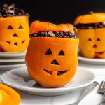 Three stuffed peppers with jack-o-lantern faces.