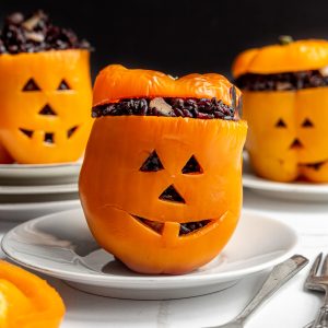 Three stuffed peppers with jack-o-lantern faces.