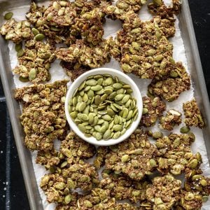 A tray of pepita brittle with a bowl of raw peptias on it.