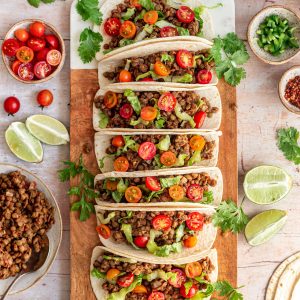 A tray of vegan lentil tacos, surrounded by toppings.