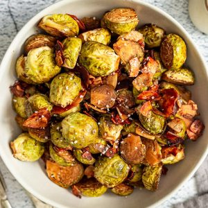 A bowl of maple balsamic brussels sprouts, tossed with coconut bacon.
