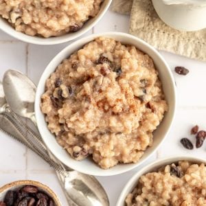 A bowl of oat milk rice pudding, topped with raisins and cinnamon.