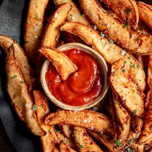 A potato wedge dipped in ketchup.