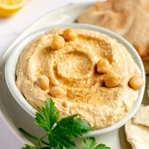 A bowl of oil-free hummus on a plate of pita bread.