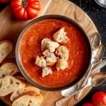 A bowl of roasted tomato soup, topped with croutons.