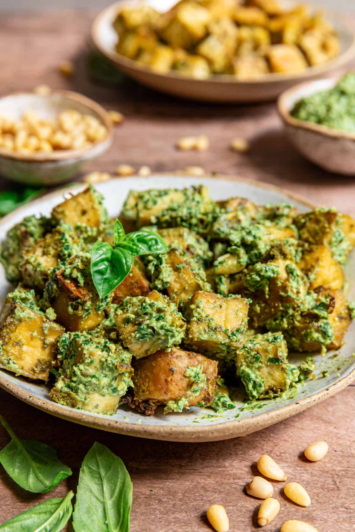 A bowl of pesto tofu, tossed with pesto and garnished with fresh basil.