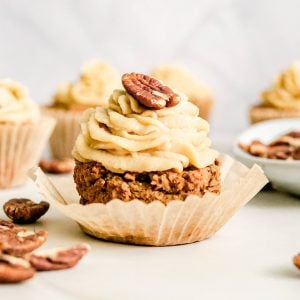 A maple pecan cupcake frosted and topped with a pecan.