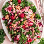 Raspberry walnut kale salad with raspberry vinaigrette drizzled on top.