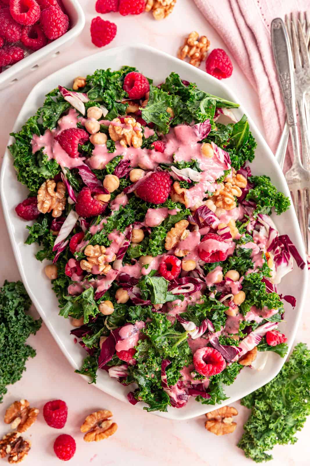 Raspberry walnut kale salad with raspberry vinaigrette drizzled on top.