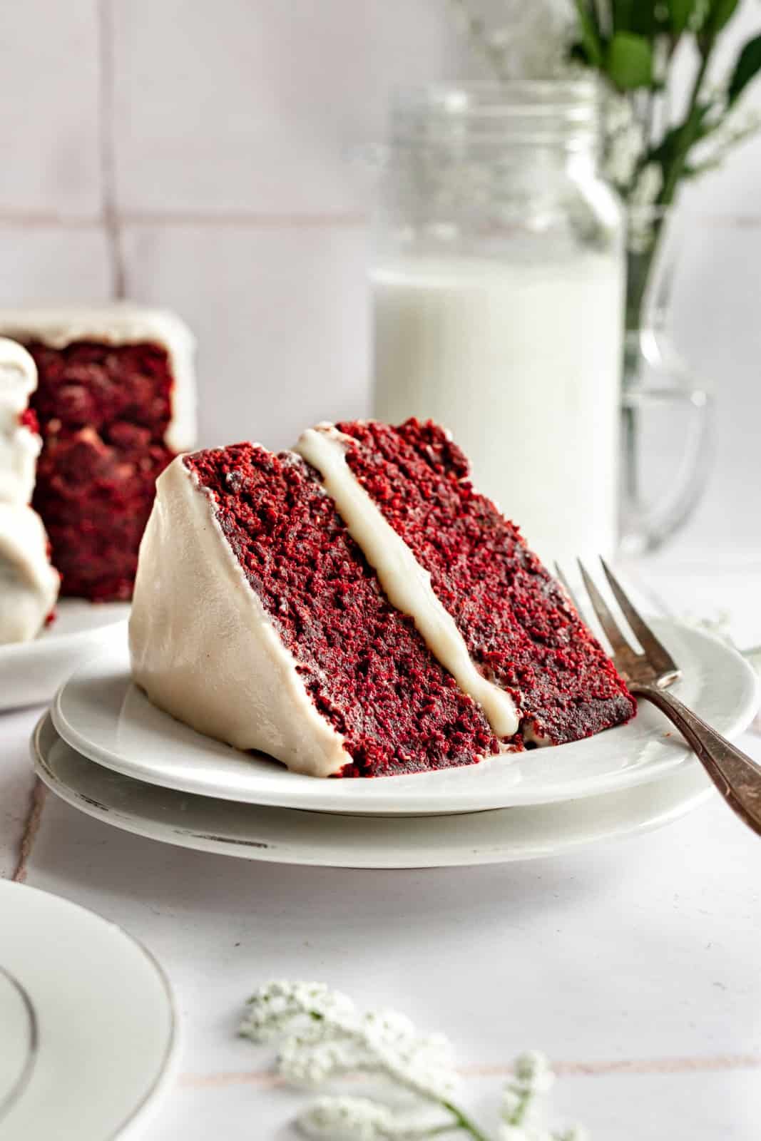 A large slice of red velvet cake, with a fork, ready to serve.