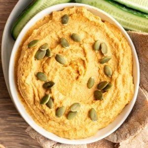 A bowl of pumpkin hummus topped with pepitas.