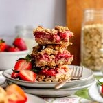 A stack of vegan strawberry crumble bars on a plate.