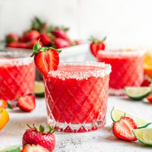 Three glasses of strawberry margarita moctkails, garnished with strawberries.