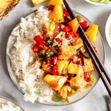 A plate of sweet and sour tofu with pineapple, served with rice.