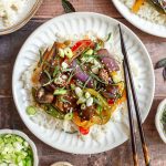 A plate of Thai Basil Eggplant Stir Fry served over rice, with chopsticks, ready to eat.