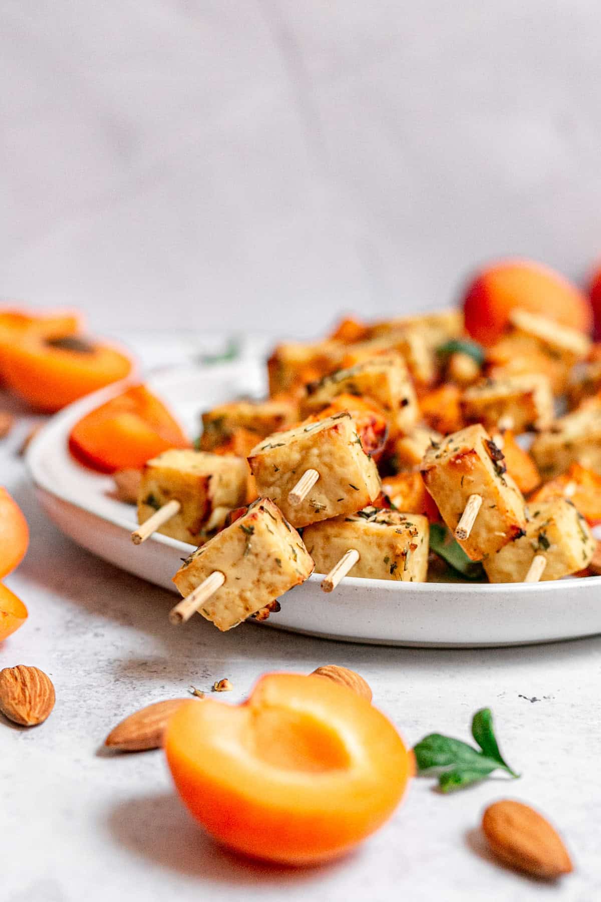 Tofu skewers hanging off the edge of a plate.